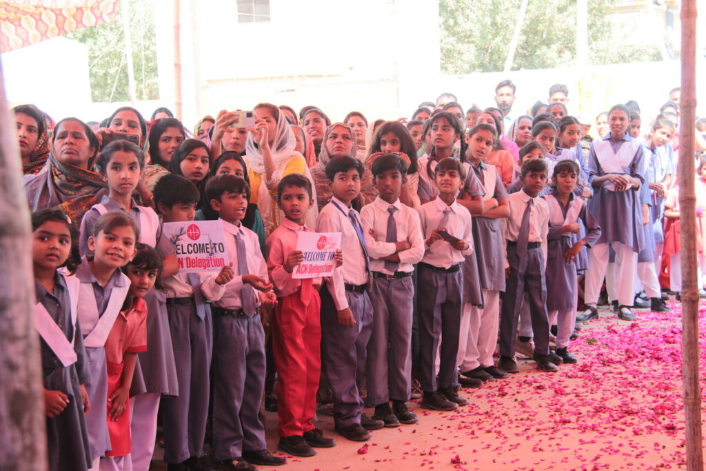 Schulkinder in Pakistan begrüßen gemeinsam mit Erwachsenen eine Delegation von KIRCHE IN NOT (ACN).