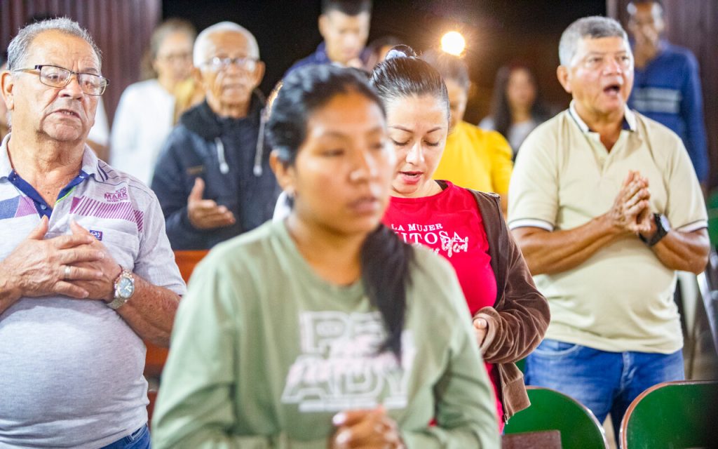 Gläubige Frauen und Männer beten gemeinsam während eines Gottesdienstes in einer Kirche.