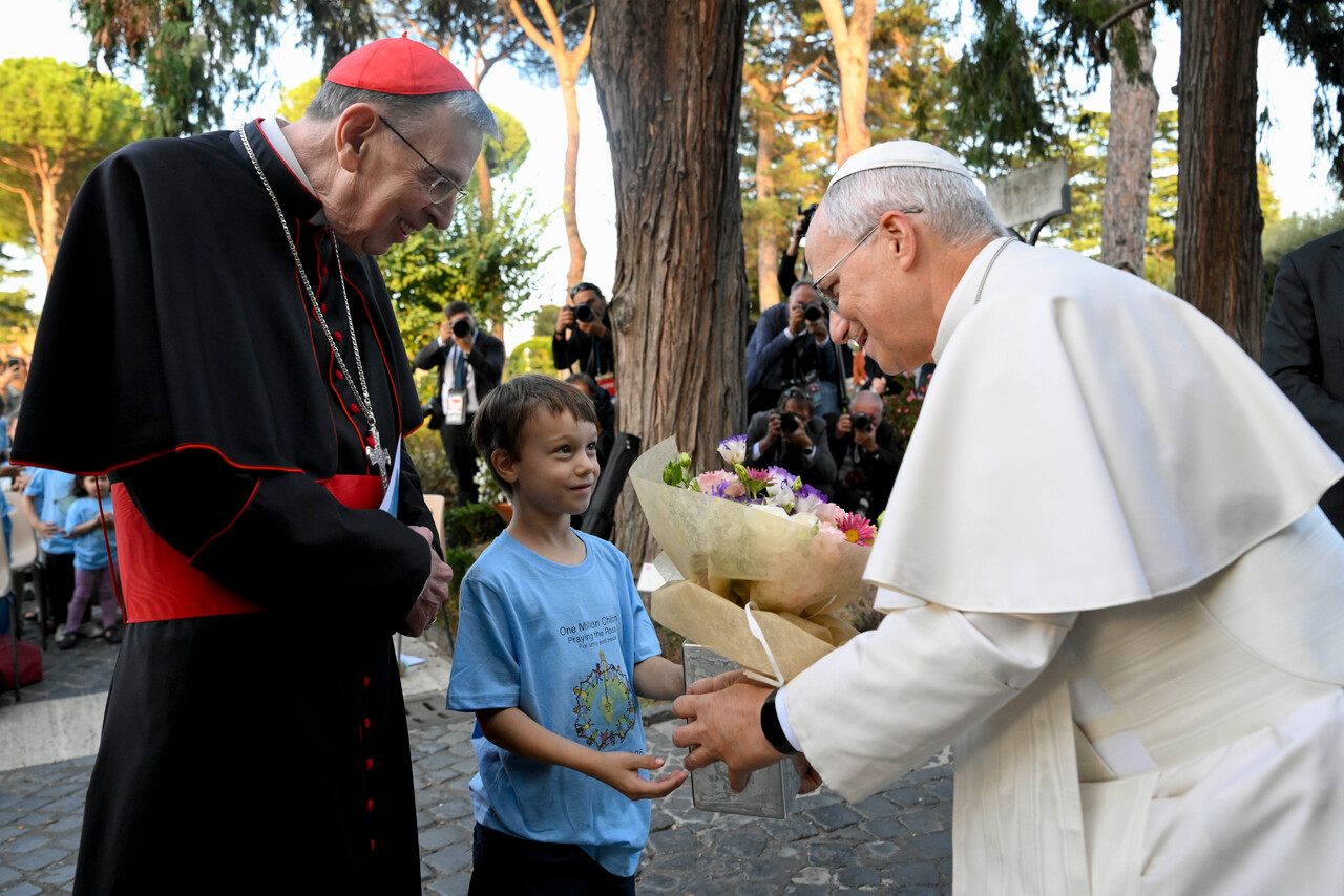 Papst Leo XIV. nimmt bei der Gebetsaktion ‚Eine Million Kinder beten den Rosenkranz‘ einen Blumenstrauß von einem Jungen entgegen.