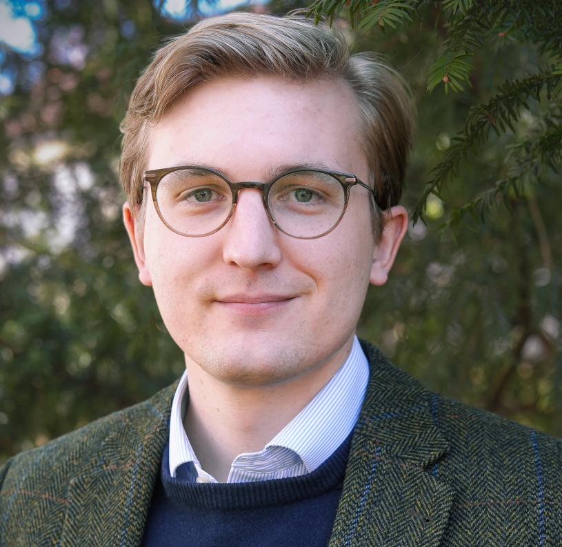 Porträt Johannes Moussong, Ehrenamtsmanager bei KIRCHE IN NOT. Im Hintergrund sind unscharfe Bäume zu sehen.“