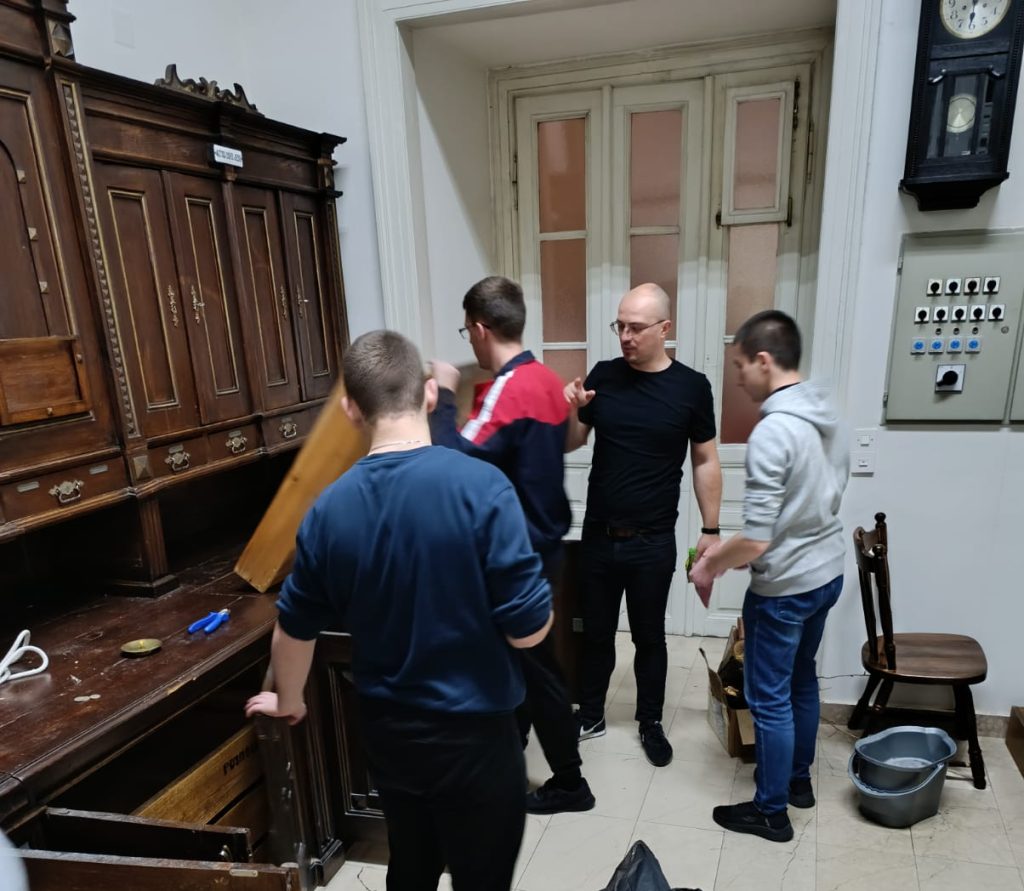 Mehrere Freiwillige räumen einen Schrank in einem kirchlichen Gebäude aus und reinigen den Raum gemeinsam.