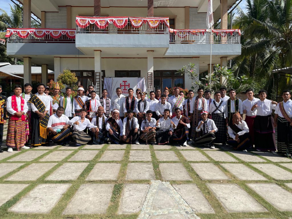 Eine große Gruppe von Seminaristen posiert gemeinsam mit Priestern und Ordensleuten vor einer Kirche für ein Gruppenfoto. Viele tragen traditionelle Kleidung aus Indonesien.